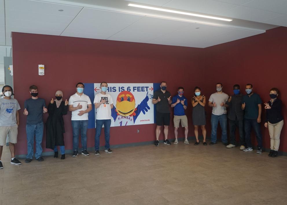 Members standing in  front of Jayhawk sign in Gray Little Hall